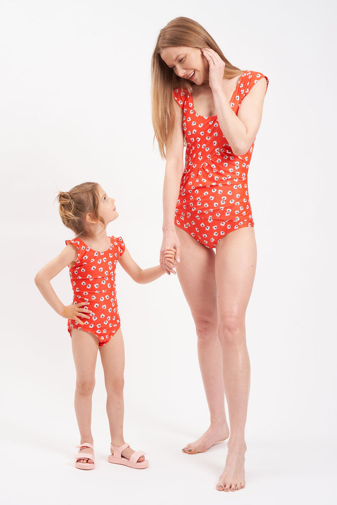 Orange little girl swimsuit with daisy pattern.