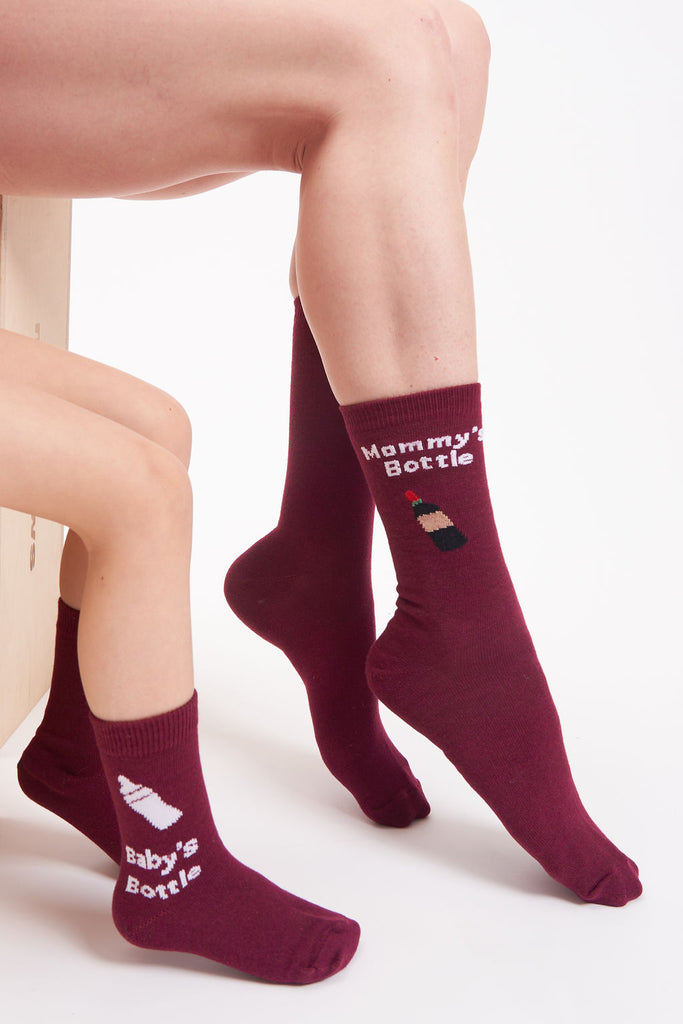 Wine red, women’s socks. Graphic of wine bottle on the adult socks with a graphic of a baby bottle on the kid socks.